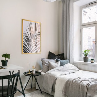 Nordisk inredning av ett litet gästrum, med vita väggar, beiget golv och ljust trägolv