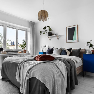 Inredning av ett minimalistiskt mellanstort huvudsovrum, med vita väggar, ljust trägolv och grått golv