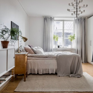Foto på ett stort skandinaviskt huvudsovrum, med vita väggar, ljust trägolv och beiget golv