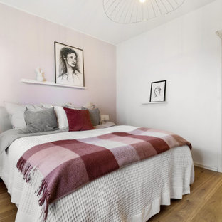 Inredning av ett nordiskt sovrum, med rosa väggar och mellanmörkt trägolv