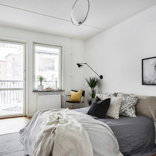 Idéer för att renovera ett minimalistiskt sovrum, med vita väggar, ljust trägolv och brunt golv