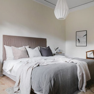 Nordisk inredning av ett sovrum, med beige väggar, ljust trägolv och beiget golv