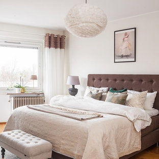Exempel på ett mellanstort minimalistiskt sovrum, med vita väggar, mellanmörkt trägolv och brunt golv