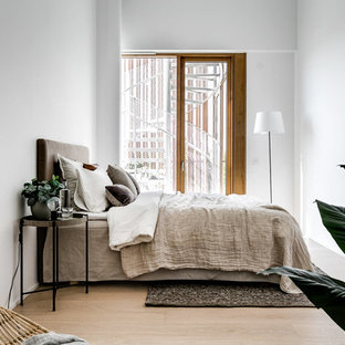 Foto på ett mellanstort nordiskt huvudsovrum, med vita väggar, ljust trägolv och beiget golv
