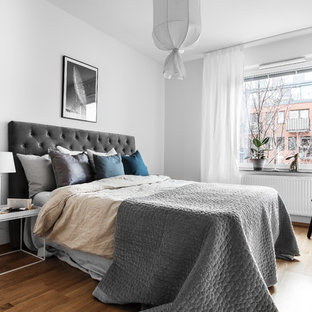 Exempel på ett minimalistiskt gästrum, med grå väggar, mellanmörkt trägolv och brunt golv