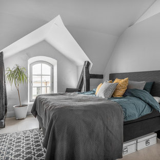 Inredning av ett minimalistiskt mellanstort huvudsovrum, med vita väggar, ljust trägolv och beiget golv