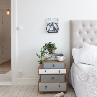 Inredning av ett minimalistiskt stort gästrum, med vita väggar och ljust trägolv