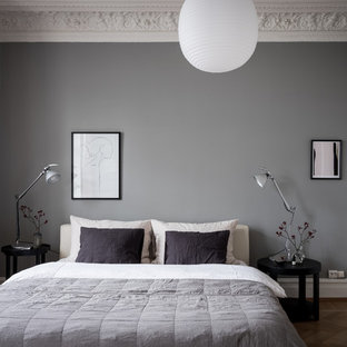 Inredning av ett minimalistiskt sovrum, med grå väggar, mellanmörkt trägolv och brunt golv