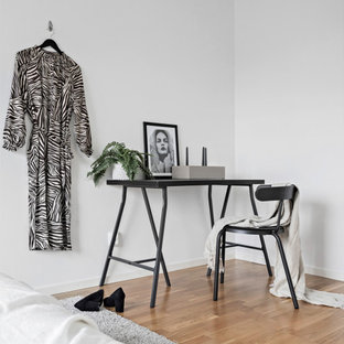 Inredning av ett minimalistiskt mellanstort huvudsovrum, med vita väggar, ljust trägolv och beiget golv