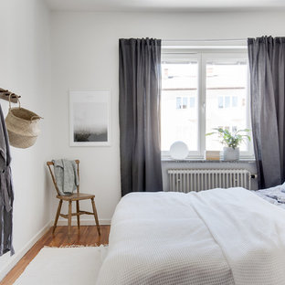 Idéer för att renovera ett minimalistiskt gästrum, med vita väggar, mellanmörkt trägolv och brunt golv