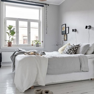 Inredning av ett minimalistiskt sovrum, med grå väggar, målat trägolv och vitt golv