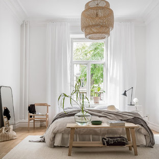 Bild på ett minimalistiskt sovrum, med vita väggar, ljust trägolv och beiget golv