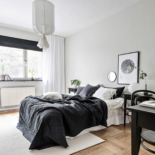 Inredning av ett nordiskt sovrum, med grå väggar, mellanmörkt trägolv och brunt golv