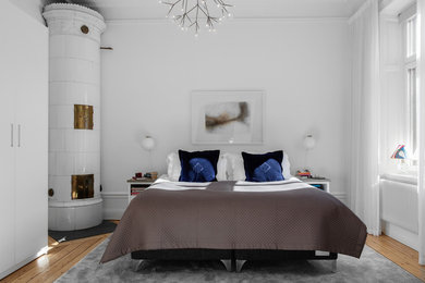 Foto de dormitorio principal escandinavo de tamaño medio con paredes blancas, suelo de madera en tonos medios, estufa de leña, marco de chimenea de baldosas y/o azulejos y suelo beige
