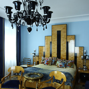 Modelo de dormitorio principal, tradicional, de tamaño medio, con paredes azules, suelo de madera clara, chimenea lineal, marco de chimenea de piedra y suelo beige