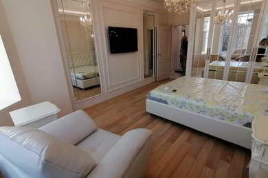 Modelo de dormitorio principal clásico de tamaño medio con paredes beige, suelo de madera en tonos medios, suelo beige y bandeja