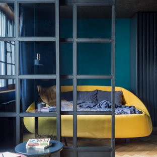 Modelo de dormitorio principal, industrial, de tamaño medio, sin chimenea, con paredes azules y suelo de madera en tonos medios