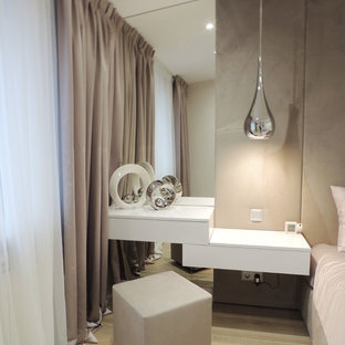 Ejemplo de dormitorio principal, actual, de tamaño medio, con paredes beige, suelo laminado y suelo beige
