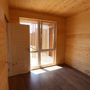 Ejemplo de habitación de invitados minimalista, pequeña, con paredes blancas, suelo laminado y suelo marrón
