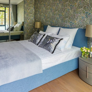 Modelo de dormitorio contemporáneo con paredes verdes y suelo de madera en tonos medios
