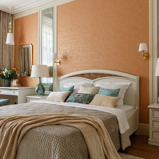Modelo de dormitorio principal, clásico renovado, con parades naranjas, suelo de madera oscura y suelo marrón