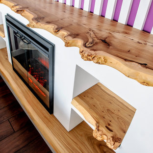 Immagine di una grande camera degli ospiti design con pareti rosa, pavimento in laminato, camino lineare Ribbon, cornice del camino in legno, pavimento marrone, soffitto ribassato e pareti in legno