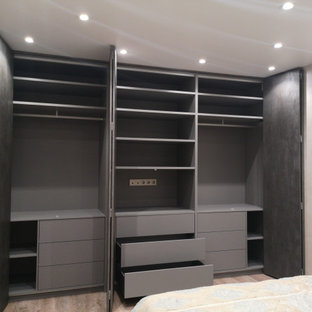 Diseño de dormitorio principal, contemporáneo, grande, sin chimenea, con paredes negras, suelo de madera en tonos medios, marco de chimenea de hormigón y suelo beige
