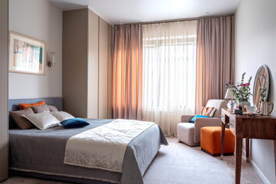 Modelo de dormitorio principal actual de tamaño medio con paredes beige, suelo de madera en tonos medios y suelo marrón
