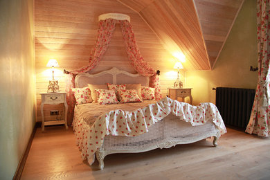 Ejemplo de dormitorio principal de estilo de casa de campo de tamaño medio con paredes verdes y suelo de madera clara