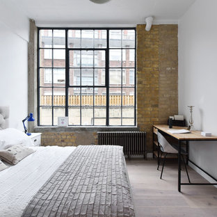 Urban bedroom in London with white walls, light hardwood flooring and beige floors.