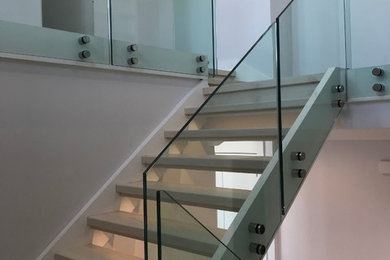 Diseño de escalera en U moderna extra grande con escalones de madera, contrahuellas de madera y barandilla de vidrio