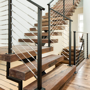 Ejemplo de escalera en L, contemporánea, sin contrahuella, con escalones de madera y barandilla de cable