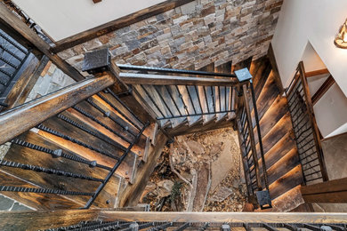 Foto de escalera en U con escalones de madera, contrahuellas de madera y barandilla de metal