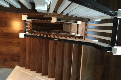 Photo of an expansive rustic wood spiral wood railing staircase in DC Metro with painted wood risers.