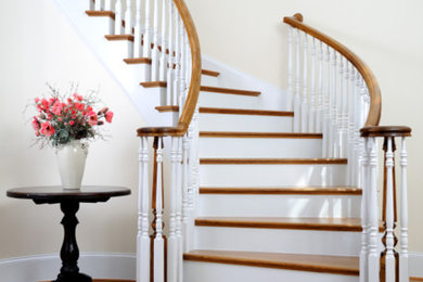 Diseño de escalera curva tradicional grande con escalones de madera, contrahuellas de madera pintada y barandilla de madera