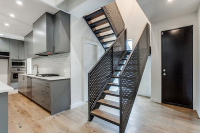 Diseño de escalera en U moderna grande con escalones de metal, contrahuellas de madera y barandilla de metal