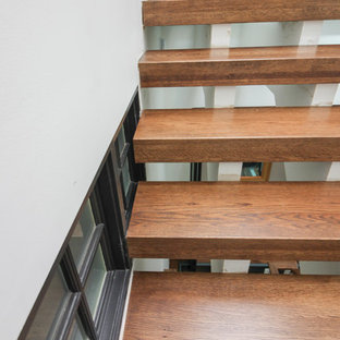 Immagine di un'ampia scala sospesa contemporanea con pedata in vetro, nessuna alzata e parapetto in vetro