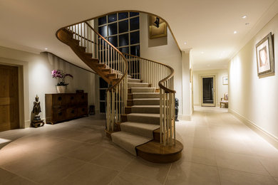 Medium sized classic wood curved staircase in Surrey with carpeted risers.