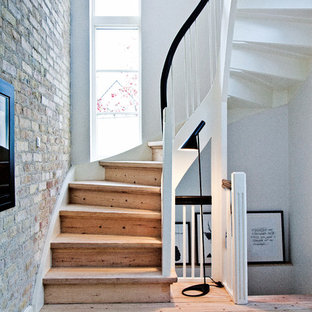 Immagine di una scala curva nordica di medie dimensioni con pedata in legno e alzata in legno