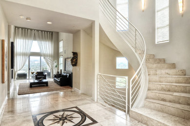 Mid-sized minimalist limestone curved metal railing staircase photo in Orange County with limestone risers