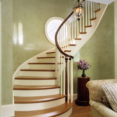 Example of a classic wooden curved staircase design in New York with painted risers