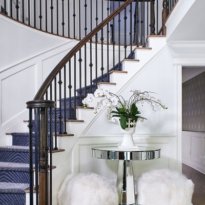 Example of a transitional wooden curved metal railing staircase design in New York with painted risers