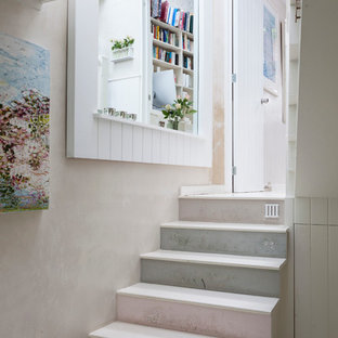 Example of a cottage chic painted straight staircase design in London with painted risers