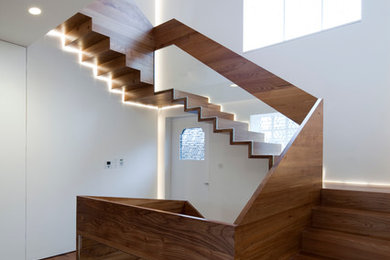 Inspiration for a contemporary wood u-shaped staircase in London with wood risers and feature lighting.