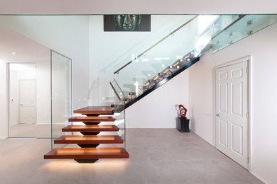 Modelo de escalera suspendida minimalista grande sin contrahuella con escalones de madera y barandilla de vidrio