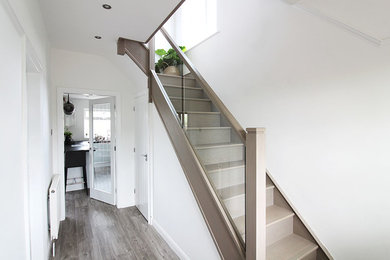 Medium sized scandinavian wood l-shaped glass railing staircase in West Midlands with wood risers.