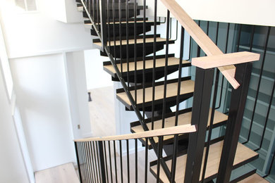 Diseño de escalera en U moderna de tamaño medio sin contrahuella con escalones de madera y barandilla de metal