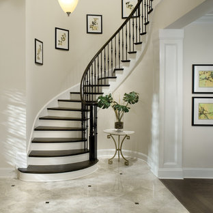 Idee per una scala curva chic con pedata in legno, alzata in legno verniciato e parapetto in metallo