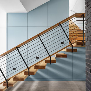 Ispirazione per una grande scala sospesa moderna con pedata in legno, nessuna alzata, parapetto in materiali misti e pannellatura