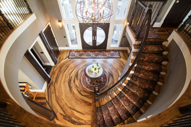 На фото: большая изогнутая лестница в классическом стиле с деревянными ступенями, крашенными деревянными подступенками и деревянными перилами